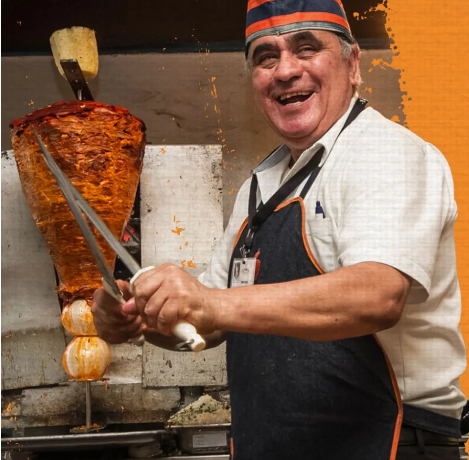 Pastorero de El Tizoncito sonriendo mientras corta carne del trompo
