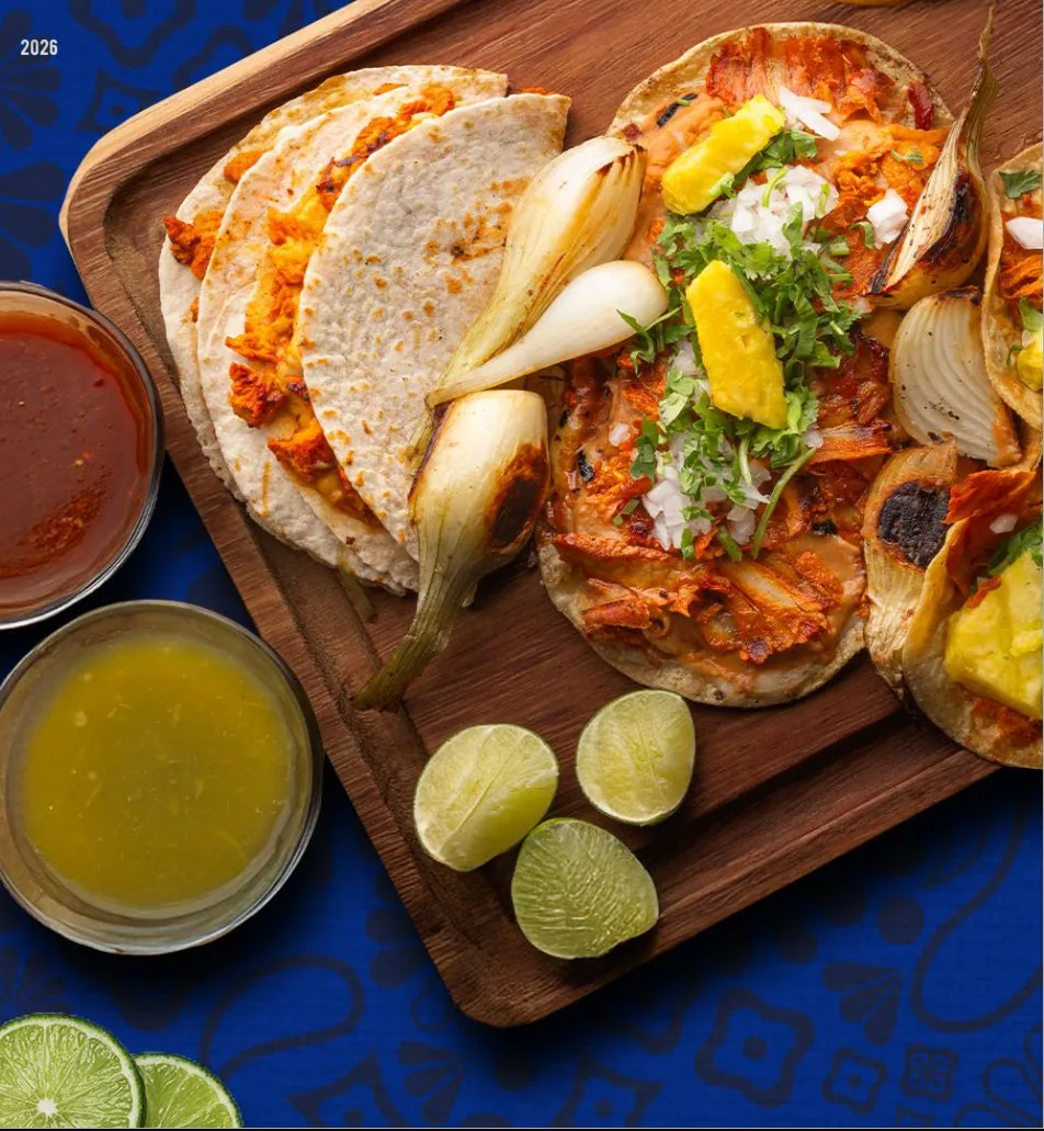 Tacos al pastor con salsas, limones y cebollitas asadas